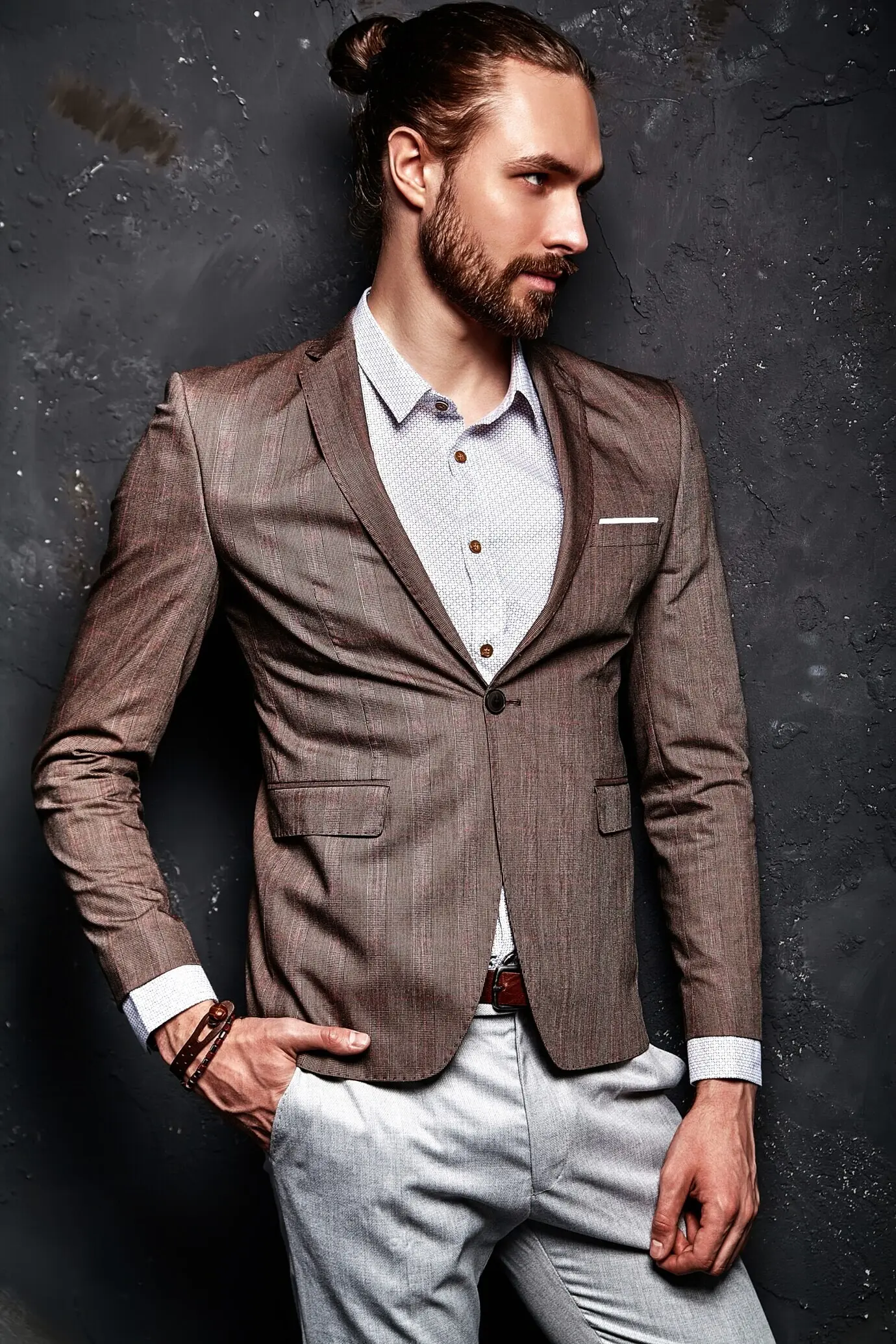 Porträt eines gutaussehenden, modischen und stilvollen Hipster-Geschäftsmann-Models, gekleidet in einem eleganten braunen Anzug, nahe einer dunklen Wand.