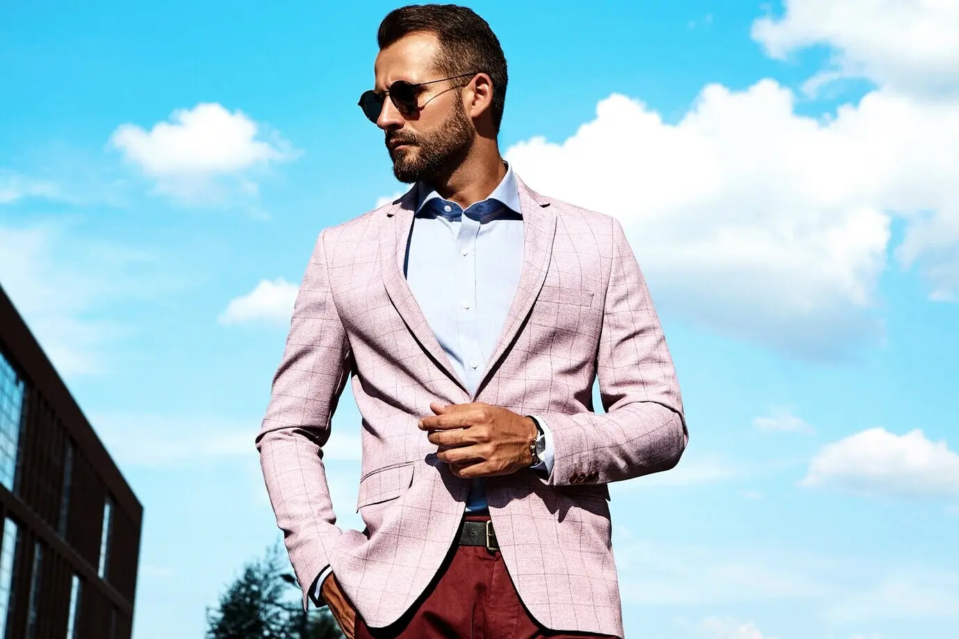 Porträt eines sexy, gutaussehenden Mode-Models als Geschäftsmann, in elegantem Anzug, posierend vor einem Straßenhintergrund. Metrosexuell.